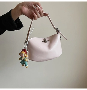 Detail of pink half-moon crossbody bag with silver clasp and cartoon girl pendant