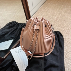 Elegant pink pleated bucket bag with metal chain strap on a black silk background