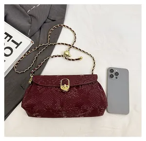 Detail view showing wine red snake skin leather texture with gold metal chain and twist lock