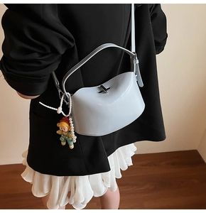 Light blue crossbody bag with pearl charm and metallic twist lock shown on model