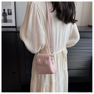 Vue mannequin d'un mini sac bandoulière rose en cuir mat avec deux boutons décoratifs
