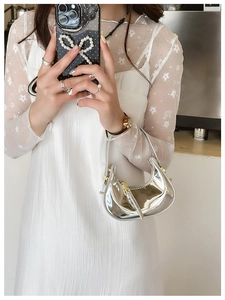 Close-up of mini silver crescent bag with metallic mirror finish worn by a model