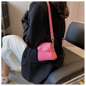 Détail d'un mini sac bandoulière rose vif avec boutons porté par un mannequin en mode
