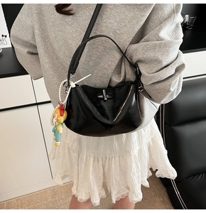 Detail of glossy black handbag with silver clasp and colorful cartoon charm