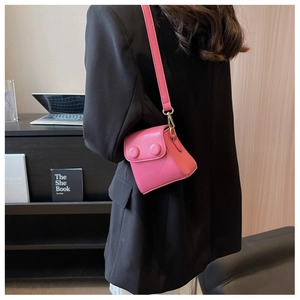 Détail d'un mini sac bandoulière rose vif avec doubles boucles rondes sur costume noir