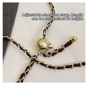 Detail of adjustable gold ball buckle on red woven leather chain shoulder strap