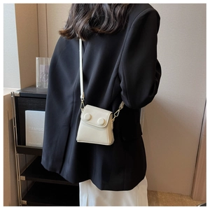 Détail d'un mini sac bandoulière crème avec de grandes boucles rondes et crochets dorés