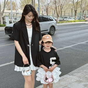 Detail of child wearing a black sequin P-letter tee and white tiered ruffle skirt