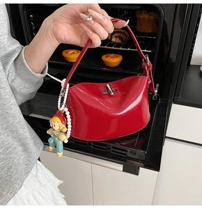 Detail of red glossy leather handbag with silver lock and pearl charm in kitchen setting