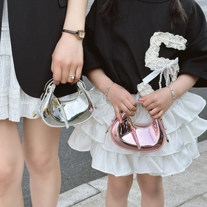 Close-up of metallic crescent mini bags in silver and pink shown by child model