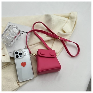 Mini sac bandoulière rose vif avec boucles rondes posé sur un blazer beige