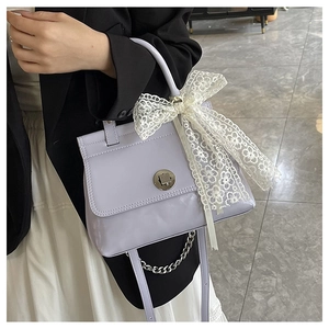 Détail du sac bandoulière lilas brillant avec nœud en dentelle blanche et fermoir métallique