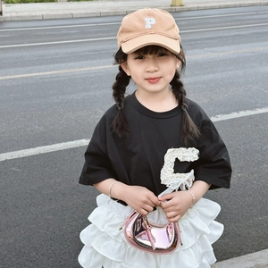 Close-up of a pink metallic crescent handbag paired with a girls fashion summer outfit