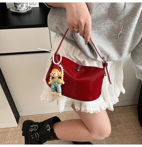 Detail of red patent leather crossbody bag with silver twist lock and doll charm