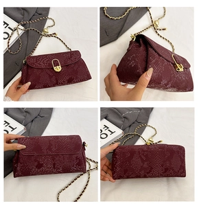 Detail view of burgundy snakeskin crossbody bag with gold hardware and chain strap