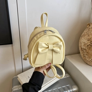 Chic cream yellow mini backpack with large bow detail and adjustable straps in lifestyle setting