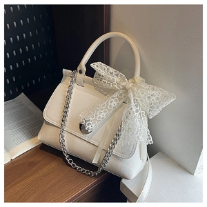 Détail du sac en cuir blanc avec grand nœud en dentelle et chaîne en métal argenté