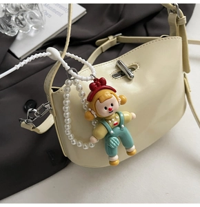 Detail of cream hobo bag with silver buckle and decorative pearl doll charm pendant