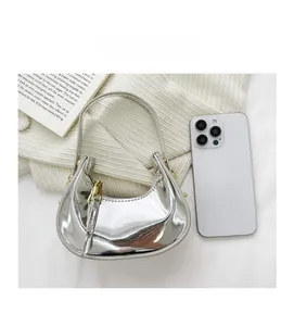 Detailed comparison of the mini silver crescent bag size relative to a smartphone