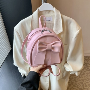 Pink PU leather mini backpack for women featuring a large decorative bow and top handle