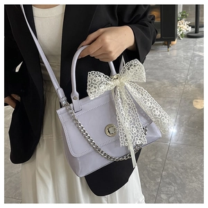 Détail du sac bandoulière lilas avec nœud en dentelle blanche et chaîne argentée
