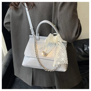 Détail du sac à bandoulière bleu clair avec fleur en dentelle et chaîne argentée