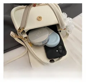Detail view of the cream saddle bag interior capacity with leather texture and gold buckle
