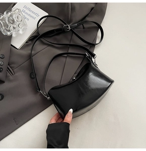 Detail of glossy black patent leather mini square bag with silver hardware on a blazer