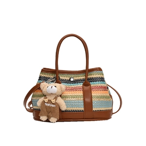 Striped woven handbag with brown leather handles and a small bear plush pendant