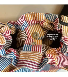 Detailed view of the magnetic closure on a striped canvas tote bag with striped lining