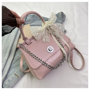 Détail du sac à main rose en similicuir avec nœud en dentelle et fermoir rotatif argenté