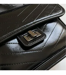 Detail of black V-quilted faux leather texture and dark gray metal twist lock buckle