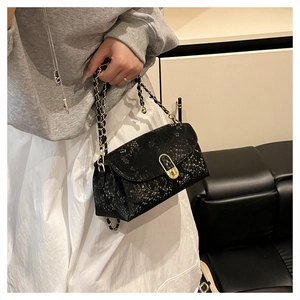 Detail of snake skin texture and gold chain strap on stylish black crossbody bag