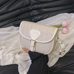 Detail of cream straw woven crossbody bag featuring white leather trim and gold hardware