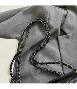 Detail of black leather and silver metal chain strap on a quilted hobo shoulder bag