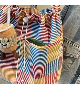 Detail of colorful striped canvas bucket bag with front pocket and plush charm