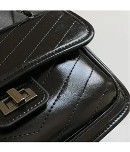 Close-up of black quilted leather texture and metallic turn-lock closure on chain bag