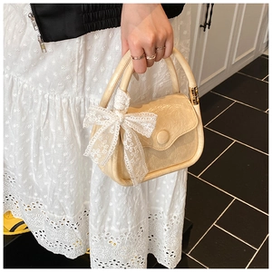 Detail of beige wrinkled texture saddle bag with elegant white lace bow decoration