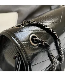 Close-up of black V-shaped quilted leather texture and silver chain eyelet detail