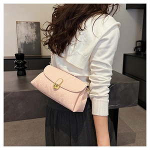 Close-up of pink snake-embossed crossbody bag with gold chain strap on a model