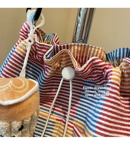 Macro detail of canvas striped bag with white drawstring closure and cupcake charm