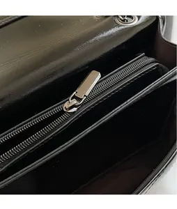 Detail of smooth metal zipper head and interior zip compartment on black leather bag