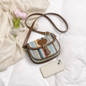 Detail of multi-color woven striped texture and brown leather strap on saddle bag