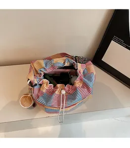 Detail of colorful striped canvas bucket bag showing large capacity and plush charm
