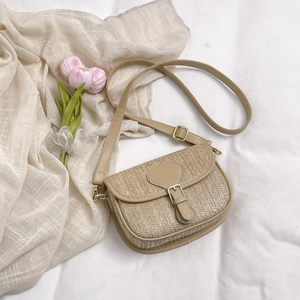 Detail of the woven straw texture and beige leather strap on this small square crossbody bag