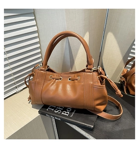 Detail of caramel brown tote bag with drawstring texture on black book and soft lighting