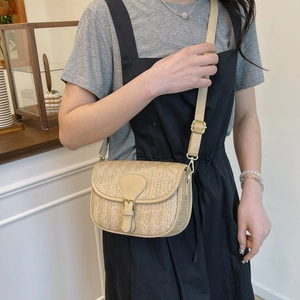 Detail of hand-woven straw crossbody bag with leather flap and golden buckle accent