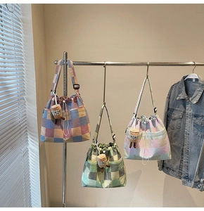Detailed view of colorful plaid canvas drawstring bags with cute plush charms and side pockets