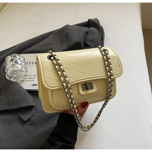 Close-up of cream quilted crossbody bag with V-shaped stitching and gold chain strap