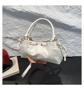 Detailed view of white textured leather Boston bag with drawstring and gold metal ring